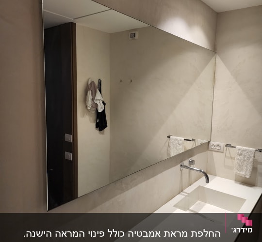 מראה גדולה מעל כיור עם ברז ומגבות